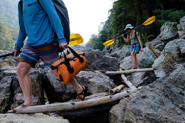 Person carrying a watershed drybag to the water carrying a paddle photo by bradengunem