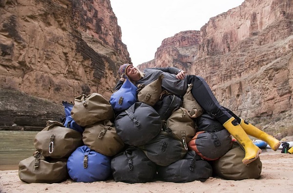 Women laying on top of many drybags outside image by tom_attwater_media