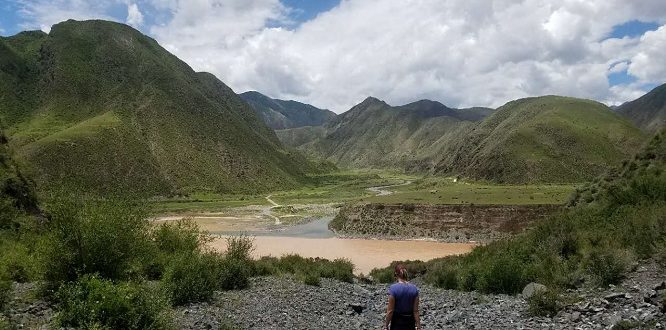 Women standing in front of a lake with mountains in the background in Tibet