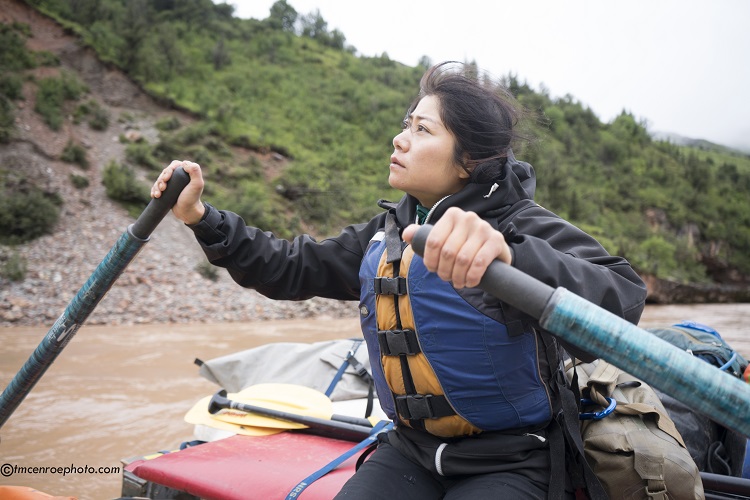 Women looking up at the sky as she paddles down the river 