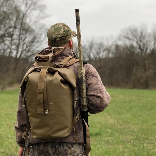 Man with an Animas Watershed Drybag on wearing all camo and a gun on his shoulder 