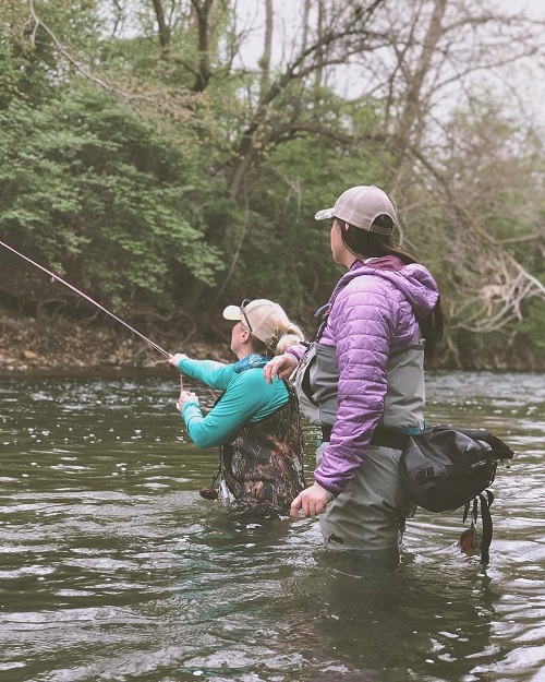 Women with a fishing pole in the water with a Watershed Drybag on her hip