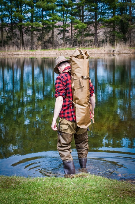 Man wearing a Rangeland™ Long Gun Backpack and stepping into a pond of water