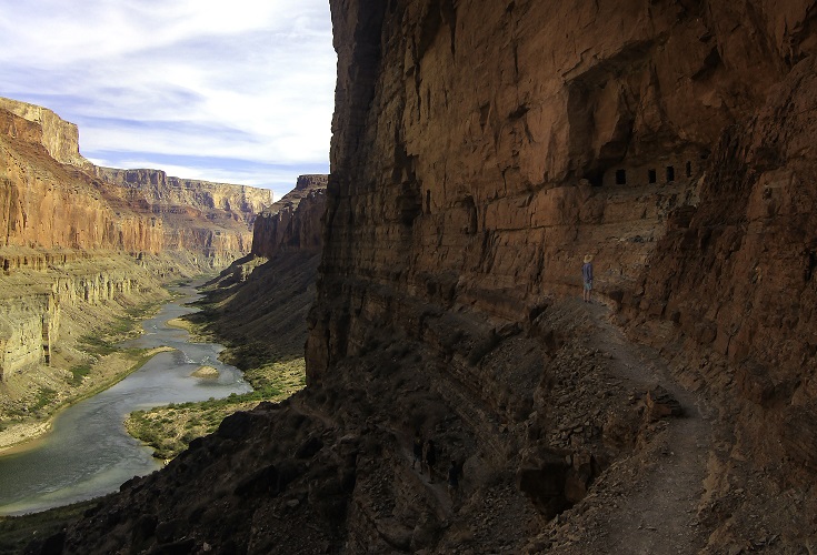 Man standing on the Grand Canyon Ledge with the river down below 