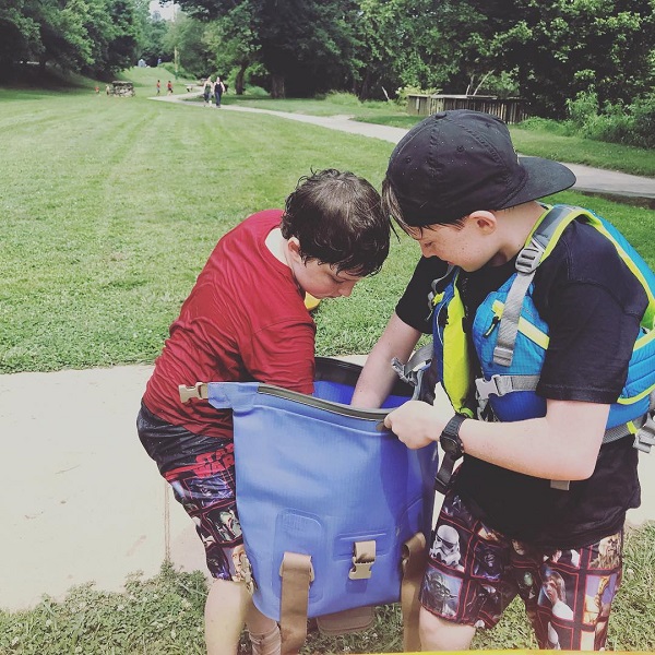 Two kids reaching into a Watershed Drybag for snacks 