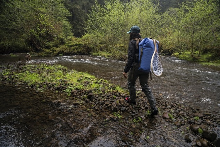 Women walking through the mossy forest with a Westwater Drybag and fishing net 