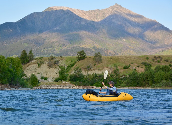 Paddling on blue waters with a mountain in the background 