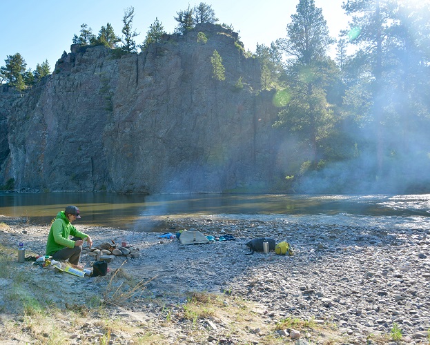 Putting out the camp fire on the banks of the river surrounded by rocks and trees
