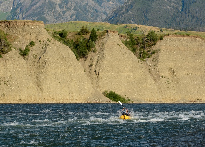 Paddling on the water with a sand cliff in the background 