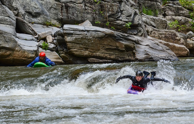 Person on a Bellyak in the river catching a wave