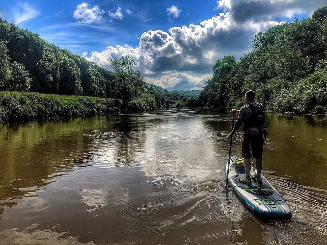 Person paddling on a SUP board through a calm river