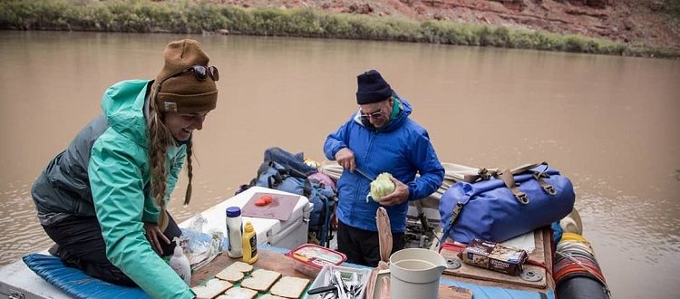 Two people preparing lunch on a raft