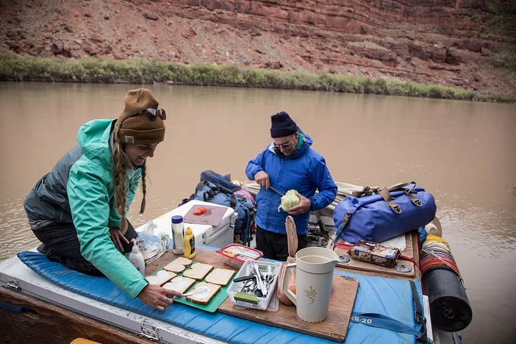 Two people making lunch on a raft with a Watershed Drybag in the picture 