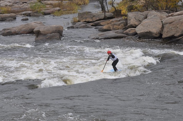 Person paddling down some whitewater on a SUP board 