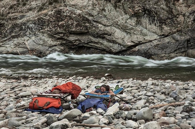 Two people sleeping on raised mats above a pile of rocks.