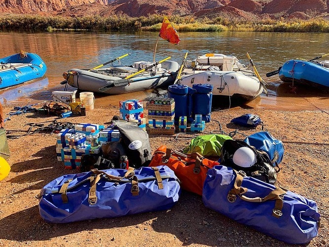 Watershed Drybags by some rafts next to the river in a canyon