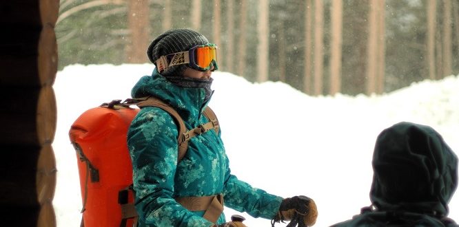 Person with trekking poles standing in the show with a Watershed Drybags Backpack