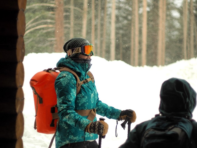 Person with trekking poles standing in the show with a Watershed Drybags Backpack